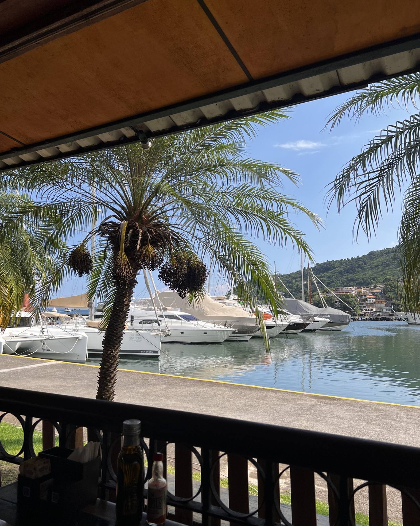 Vista do deck do BOTA Cucina na Marina Verolme, com barcos atracados e o morro de Angra ao fundo